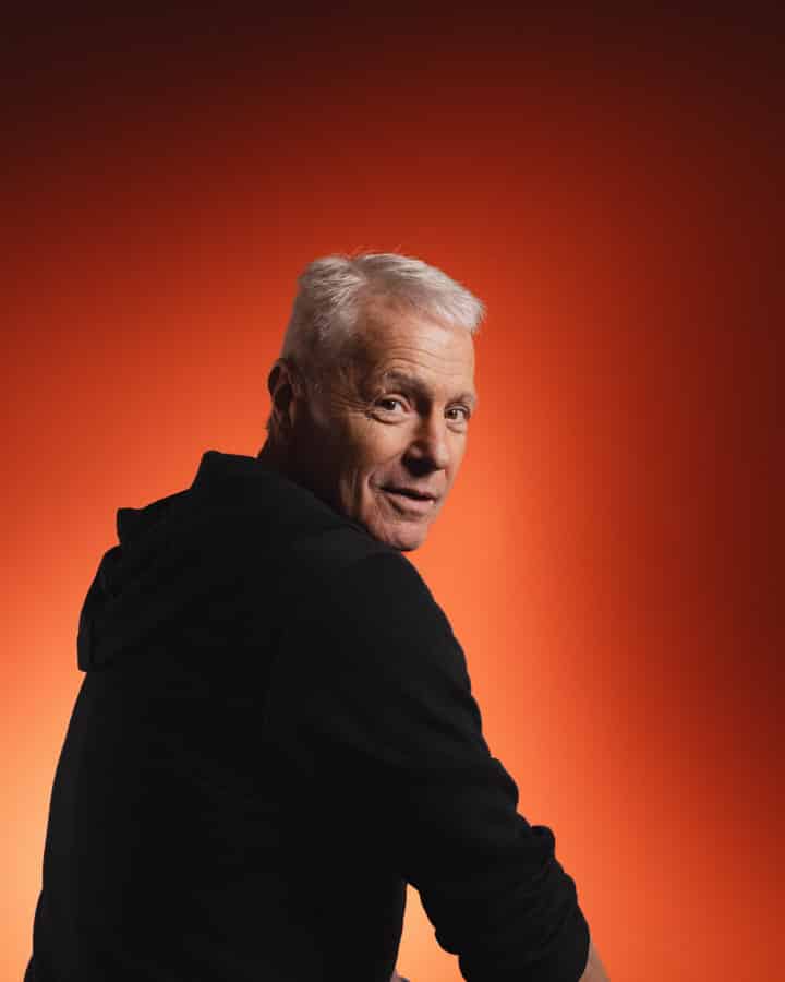 Peter Straub sitzend vor einem orange-roten Hintergrund