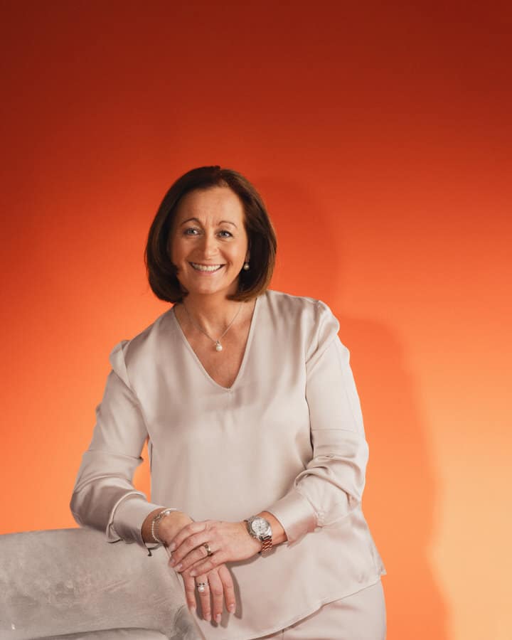 Waltraud Weratschnig stehend vor einem orange-rotem Hintergrund